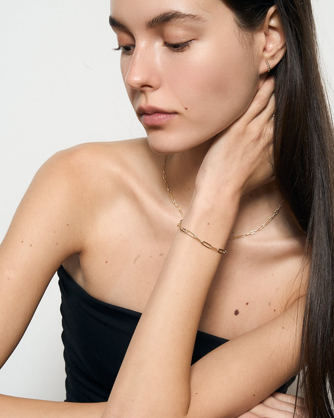 Woman wearing gold jewelry on a plain background