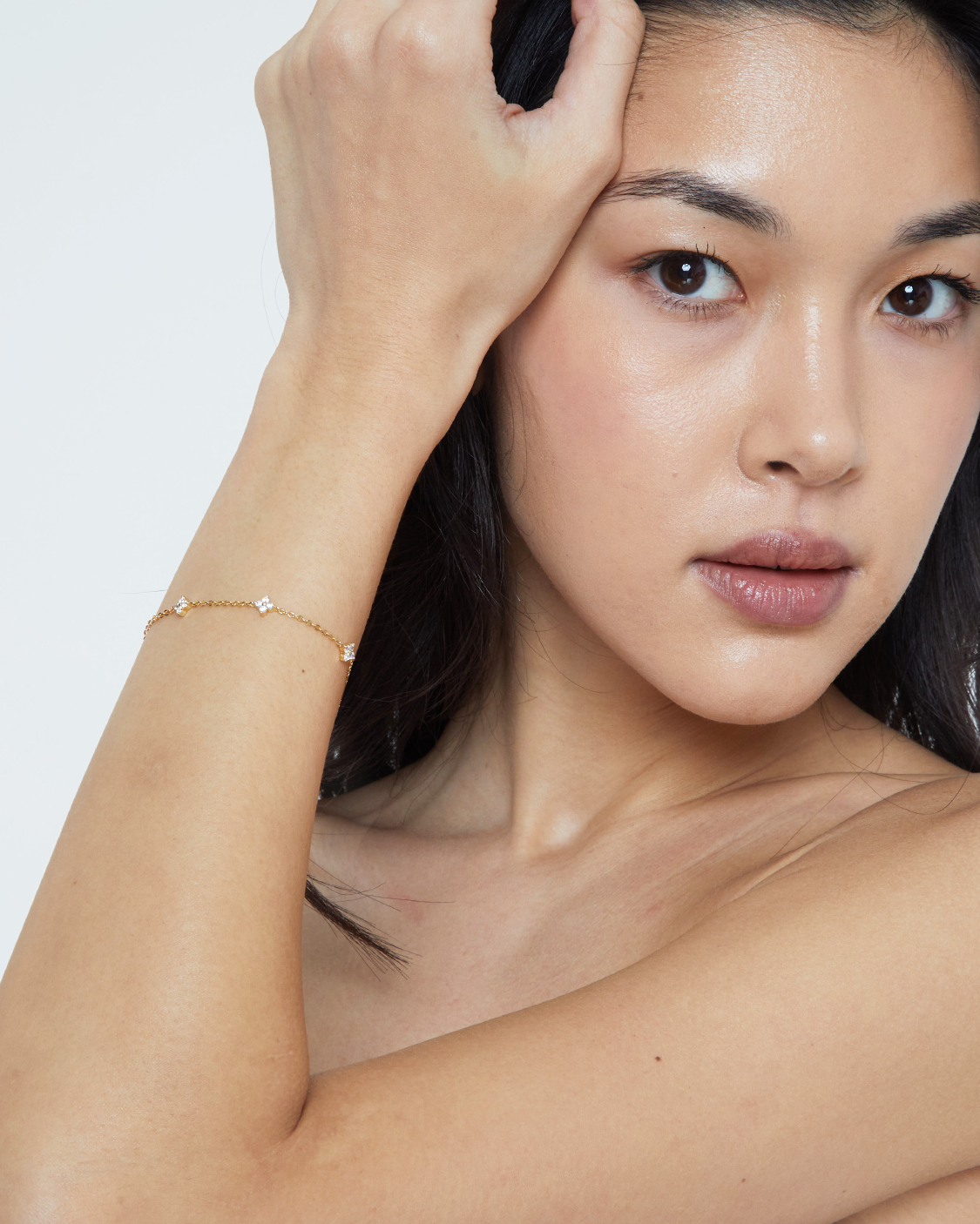 Woman with a gold bracelet on her wrist against a white background