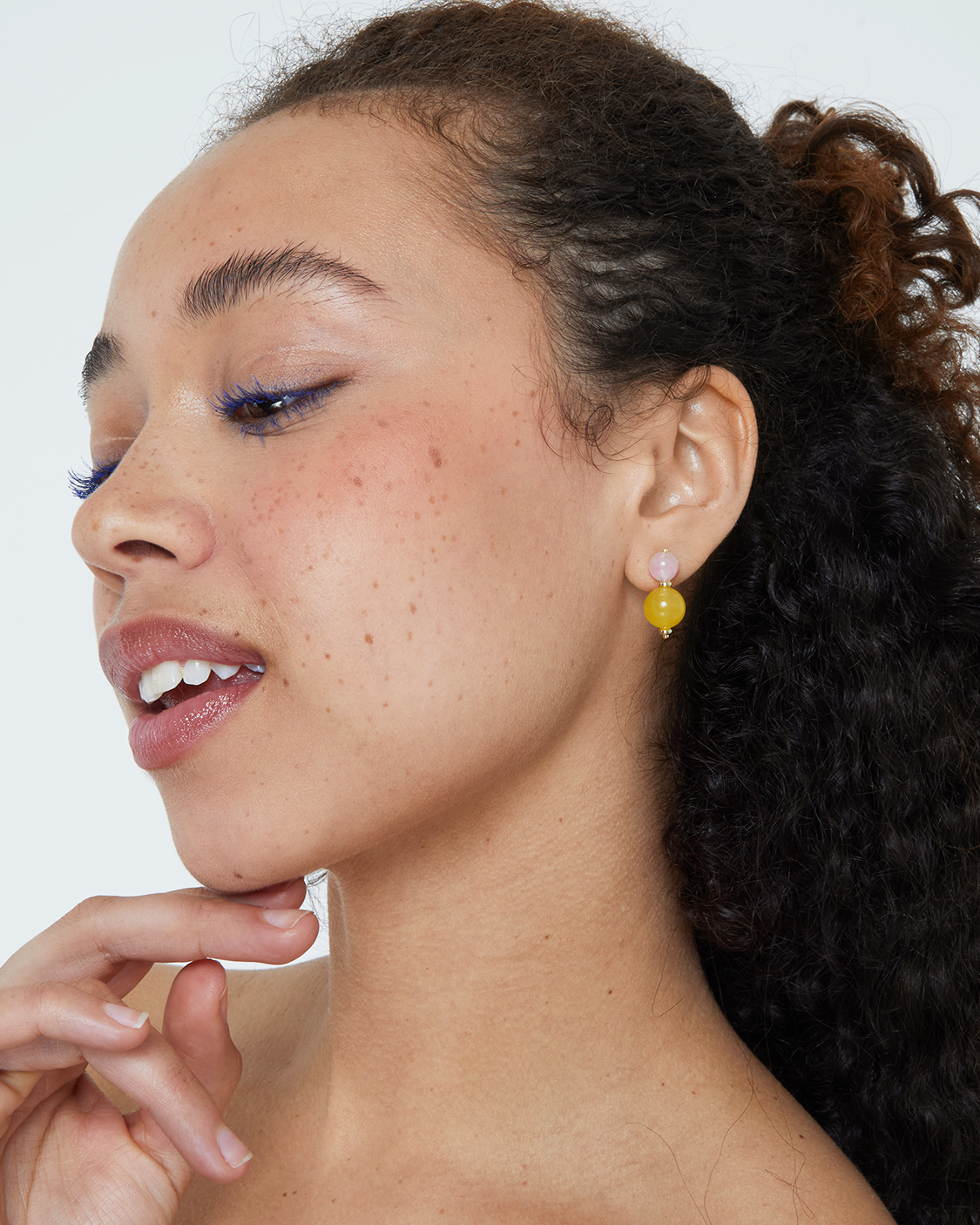 Close-up of a woman wearing orange earrings with a white background