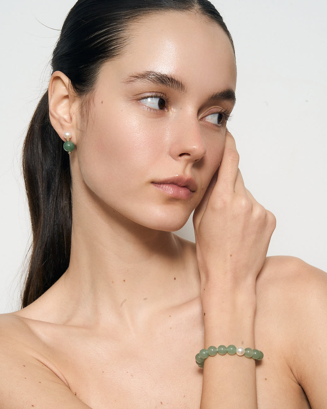 green earrings and bracelet against a white background