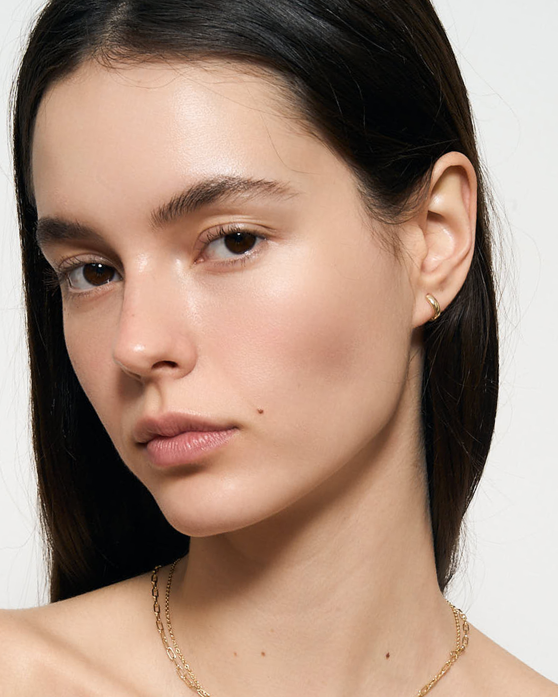 Model wearing gold huggie hoop earring