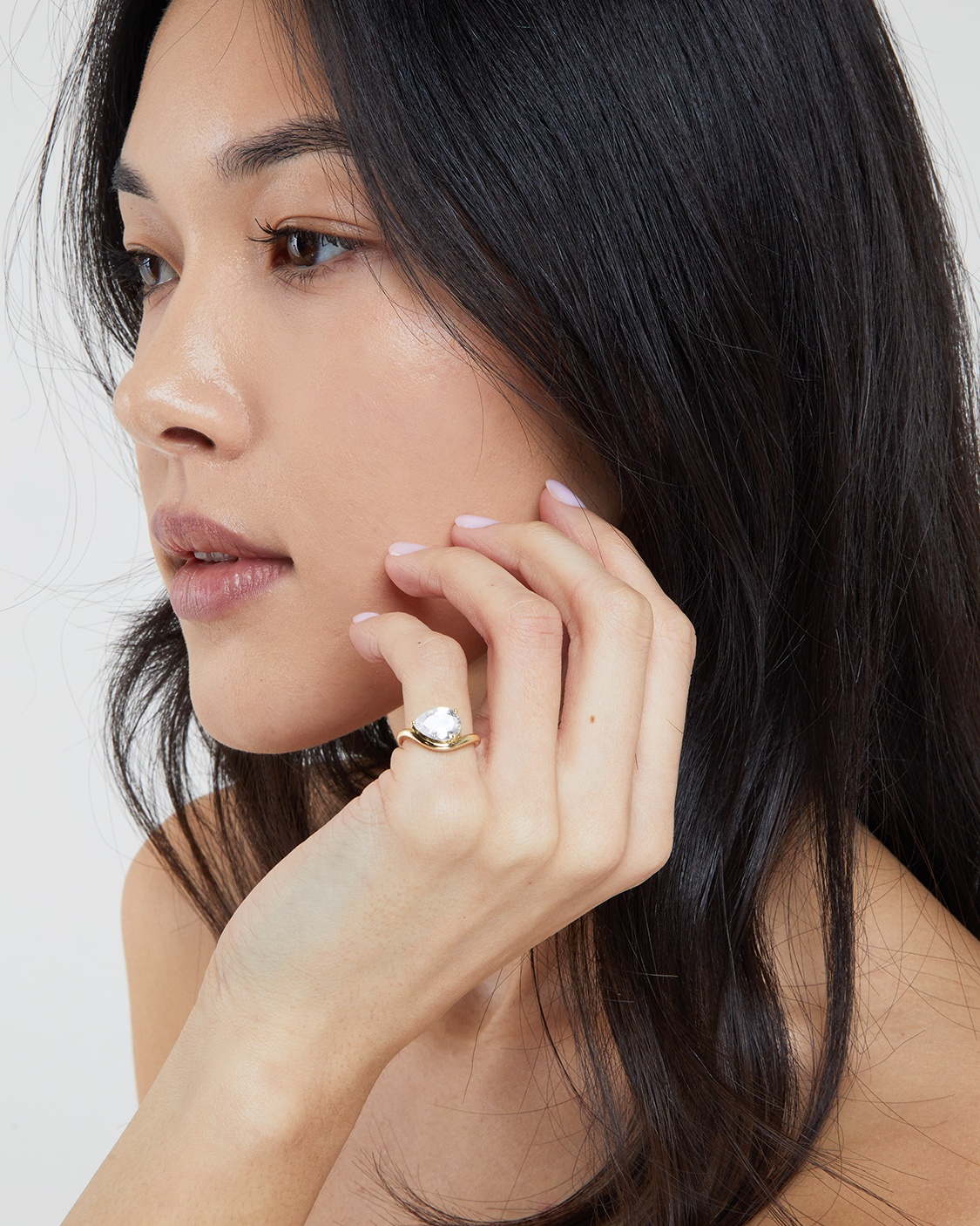 Woman wearing a gold ring on her finger with a plain background