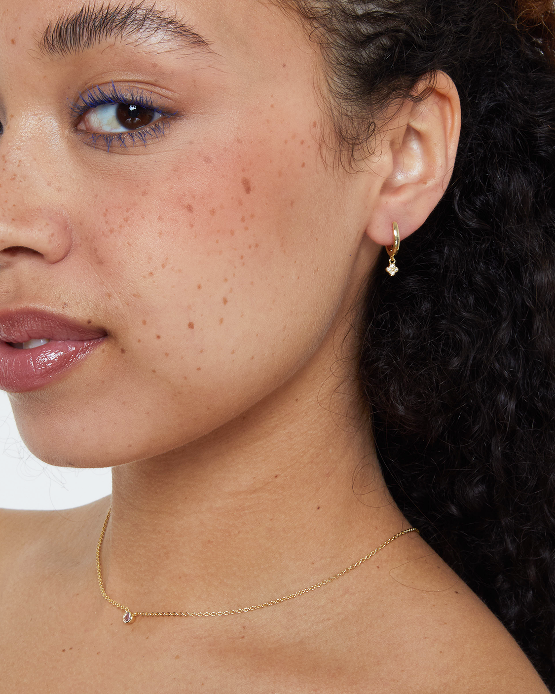 woman wearing gold hoop earrings with clover drop