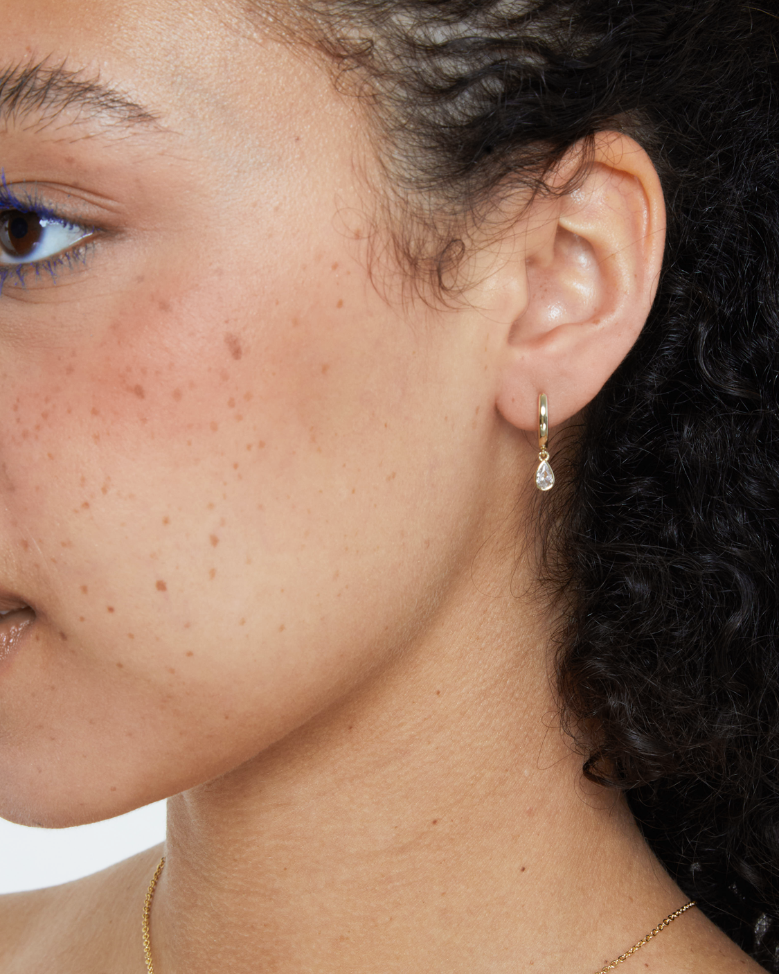 woman wearing gold huggie with teardrop drop