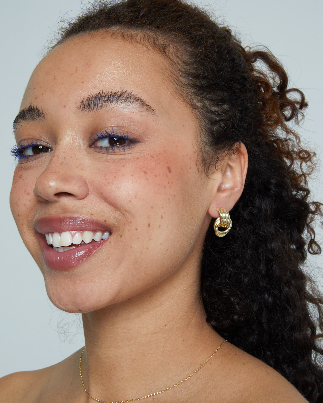woman wearing gold triple knot earrings