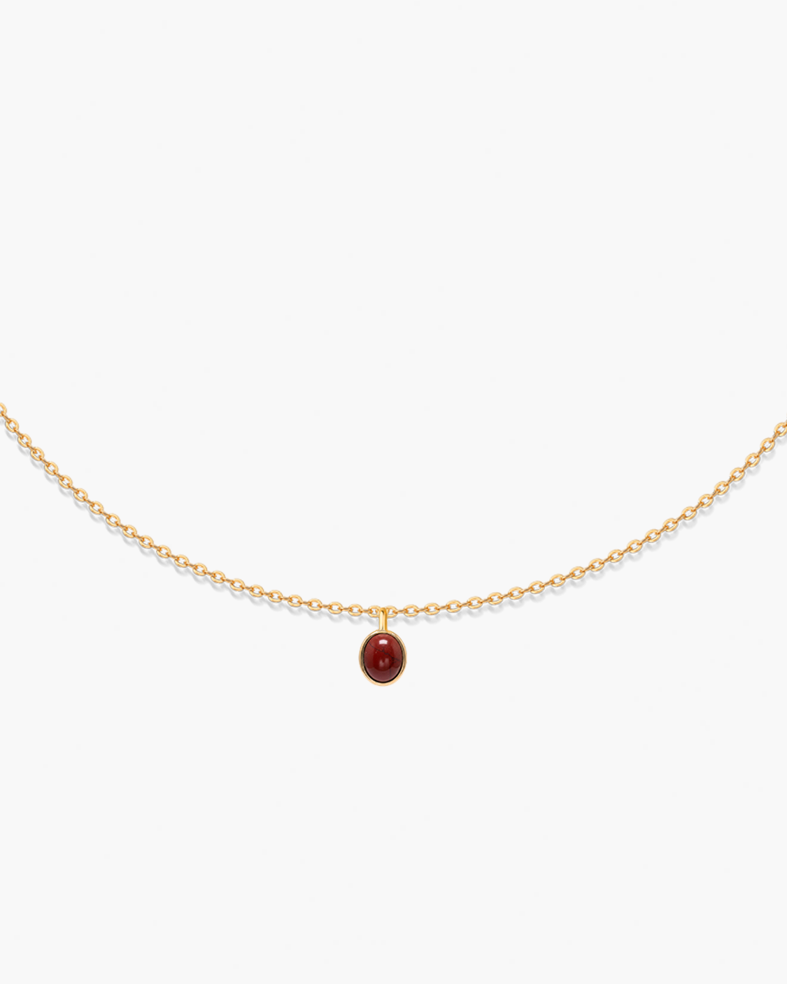Gold necklace with a red gemstone pendant on a white background