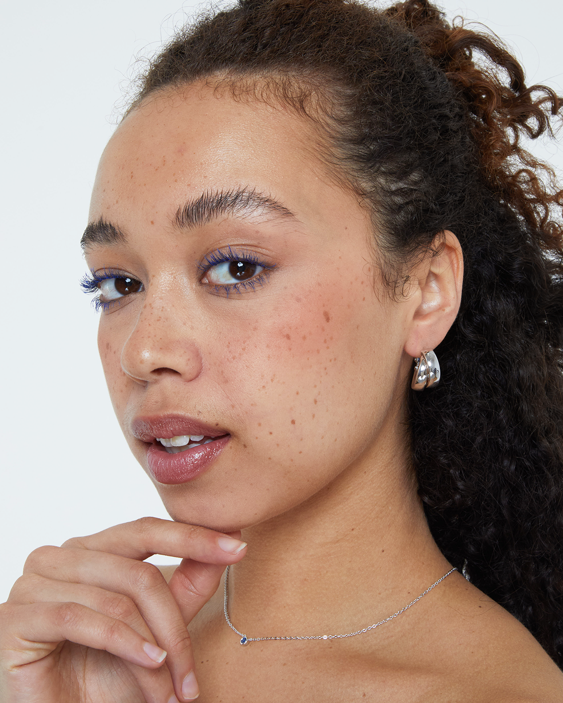 Close-up of a woman with curly hair, wearing silver earrings