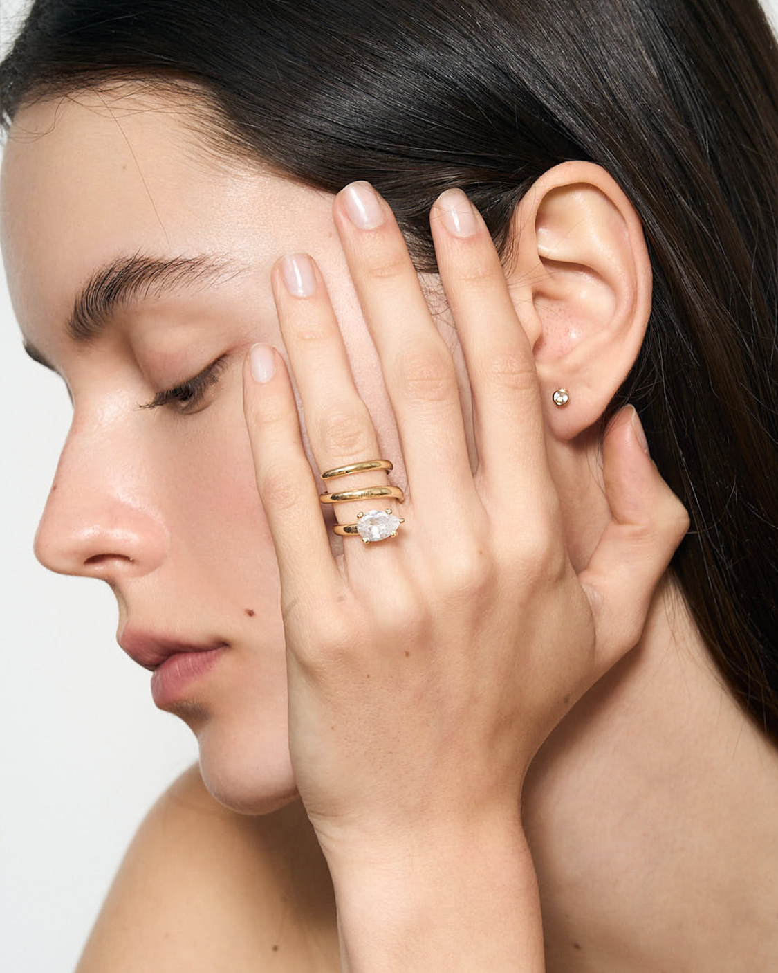 GOld spiral ring with a clear tear drop gemstone on model