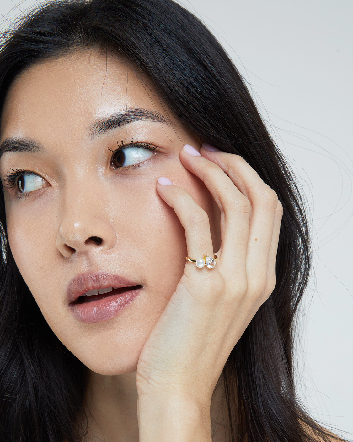 Woman wearing ring with white clear gem.